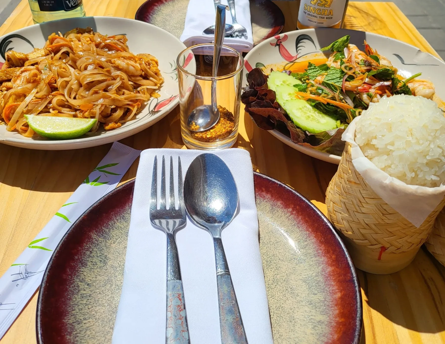 Mesa en la terraza con pad thai, ensalada de gambas y arroz glutinoso