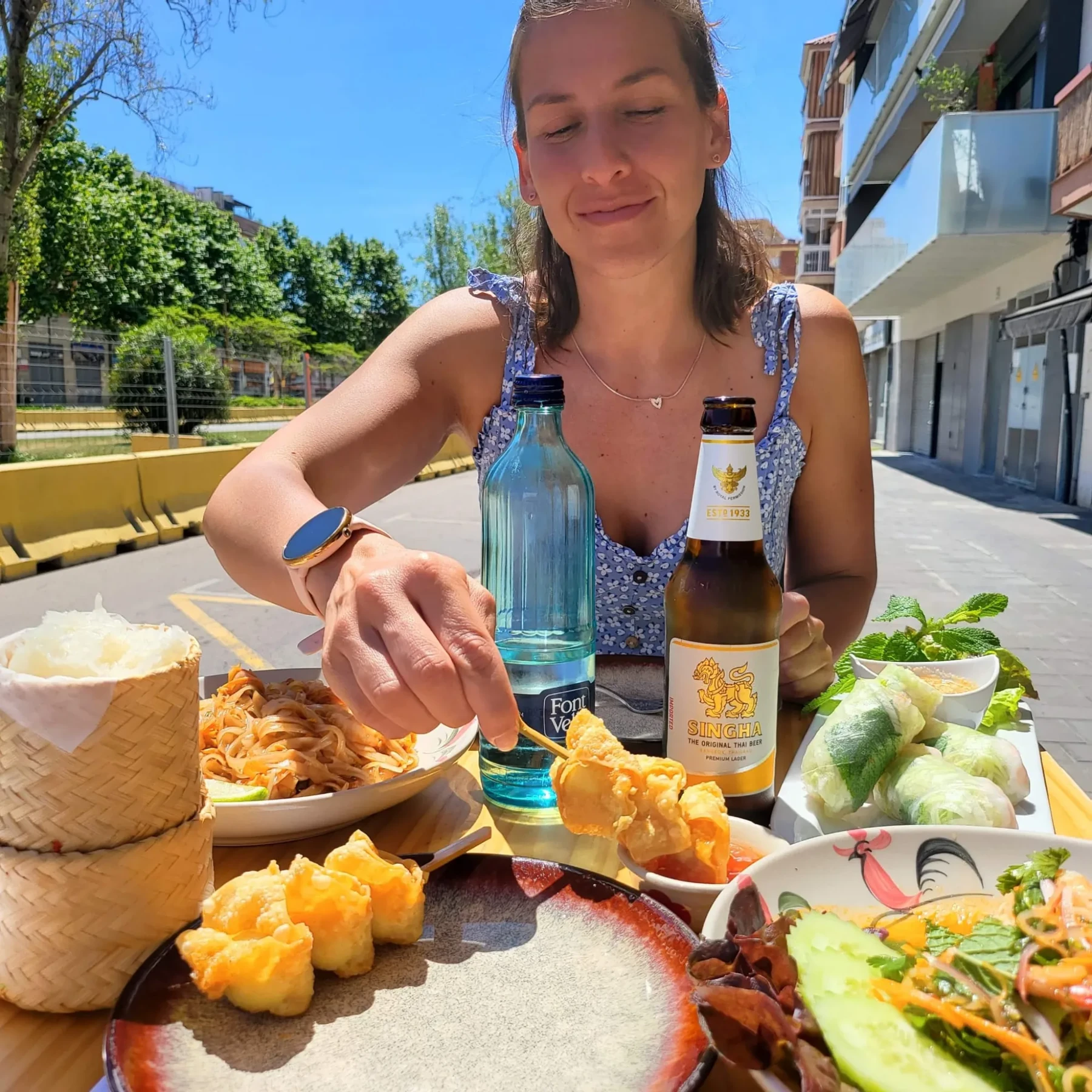 Mesa compartida en la terraza con pad thai, rollitos y ensalada